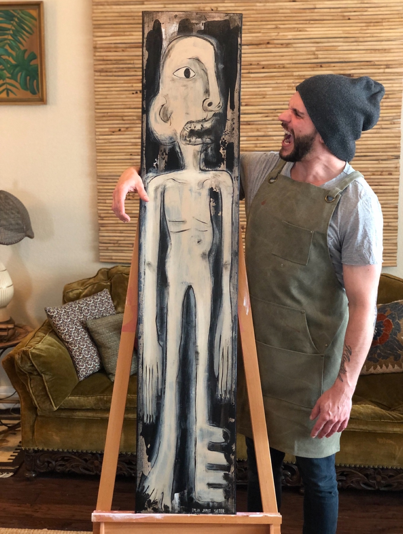 Dylan Yarter standing beside a tall black and white painting on an easel, looking at it
