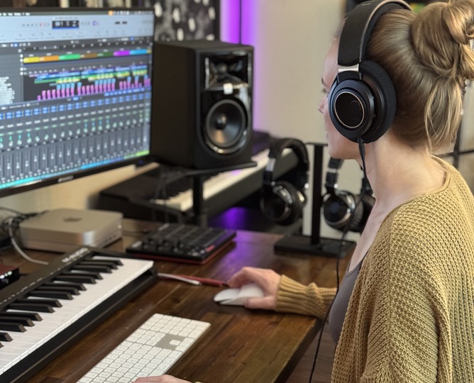 Kate Yarter in headphones at the audio workstation, a session open on screen beside the keyboard