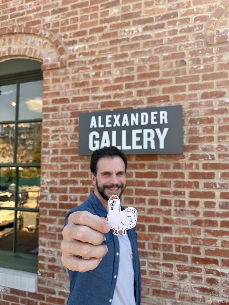 Dylan Yarter holding a chicken sticker outside the Alexander Gallery sign