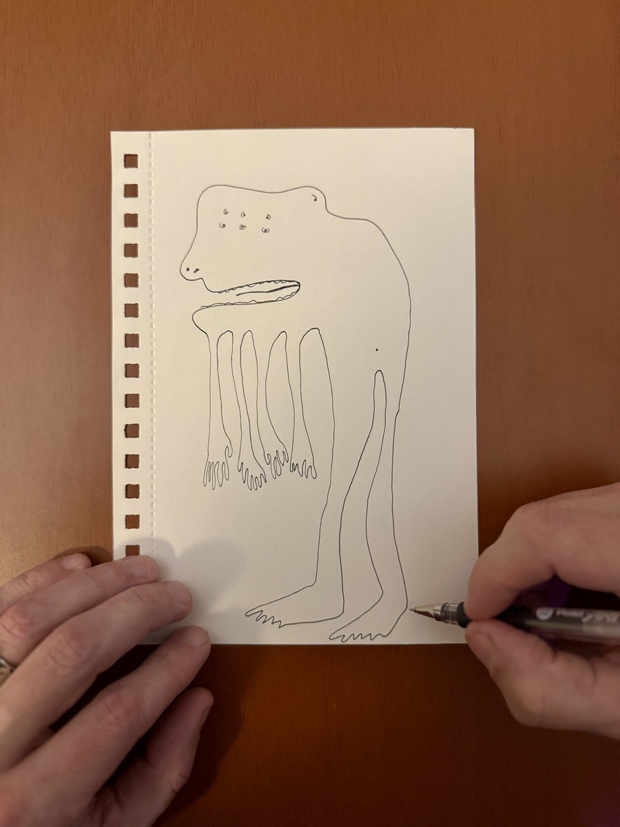 A beast drawn in one continuous line in a sketchbook, pen still on the page